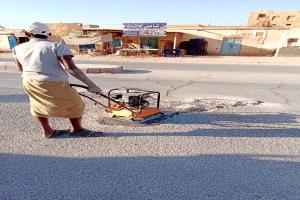 فريق الصيانة بمكتب الاشغال العامة والطرق بمديرية القطن يقوم بأعمال ردم الحفر في الاسفلت داخل المدينة و السوق التجاري